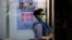 A woman wears a face mask as she walks past a poster showing how to avoid the H7N9 avian influenza virus, by a road in Beijing, April 24, 2013.