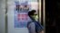 A woman wears a face mask as she walks past a poster showing how to avoid the H7N9 avian influenza virus, by a road in Beijing, April 24, 2013.