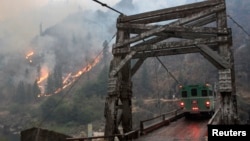 The TePee wildfire is seen burning at the Manning Bridge as it crosses the Salmon River near Riggins, Idaho, in this U.S. Forest Service picture taken Aug. 29, 2015. 