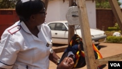 FILE - Charity Salima weighs a child at Achikondi Community Clinic in Lilongwe, Malawi. (Lameck Masina/VOA)