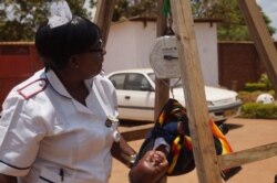 Charity Salima weighs a child at Achikondi Community Clinic in Lilongwe, Malawi. (Lameck Masina/VOA)