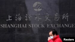 A man wearing a mask walks past the Shanghai Stock Exchange building in the Pudong financial district in Shanghai, China, as the country is hit by an outbreak of the coronavirus, Feb. 3, 2020.