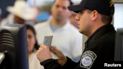FILE - A U.S. Customs and Border Protection officer checks a passport at a border crossing in San Ysidro, California, Jan. 31, 2008. A firm commissioned by U.S. Secretary of State Rex Tillerson recommends that passport and visa issuance be transferred from the State Department to the Department of Homeland Security.