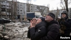 2023年2月15日，在烏克蘭頓涅茨克州，民眾站在一棟被導彈擊中嚴重受損的公寓樓前。（路透社照片）
