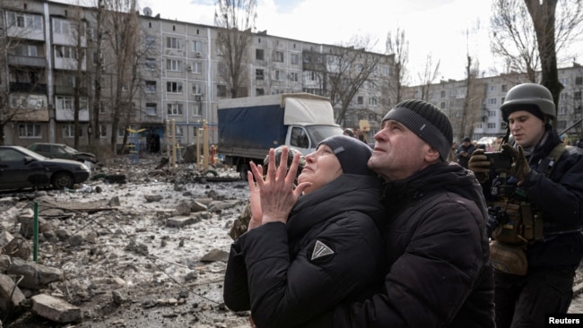 2023年2月15日，在烏克蘭頓涅茨克州，民眾站在一棟被導彈擊中嚴重受損的公寓樓前。 （路透社照片）