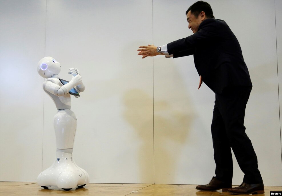 Board Director of Product Division for SoftBank Robotics Kazutaka Hasumi (R) performs with SoftBank's emotion-reading robot Pepper during a demonstration to show its compatibility with Google's Android software, at the company's headquarters in Tokyo, Japan.