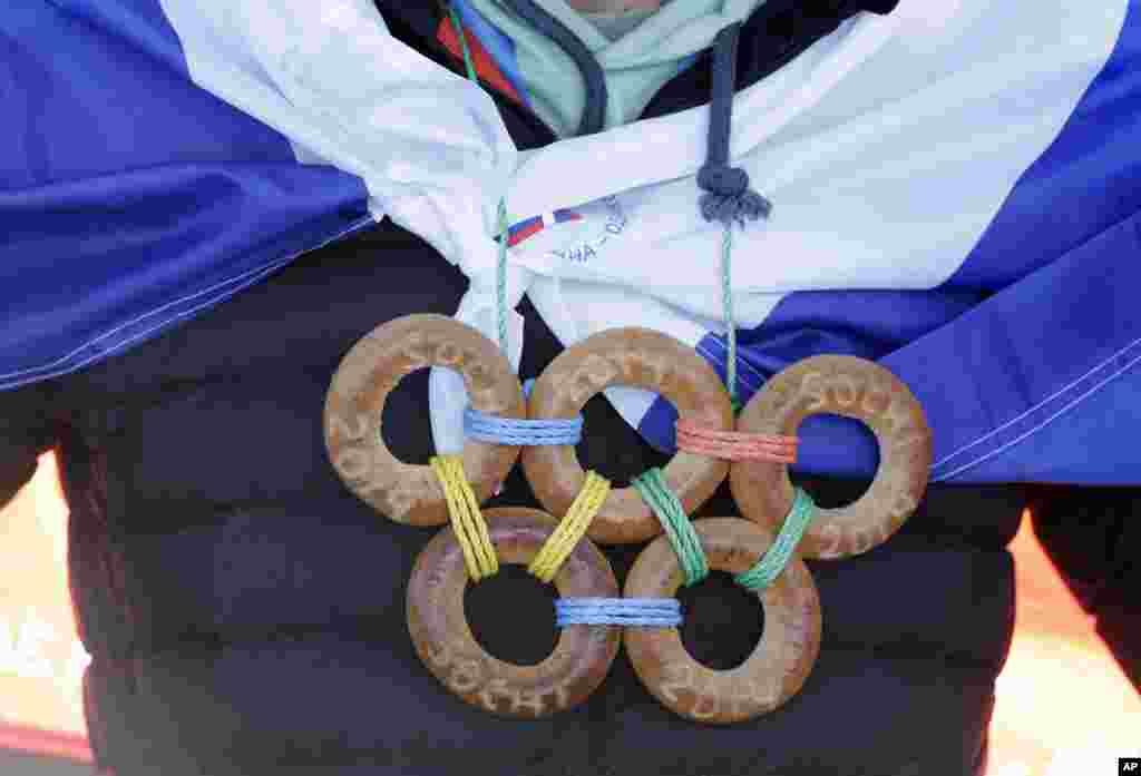 Um espectador com anéis dos olímpicos feitos com bagels (um género de biscoitos), Jogos Olímpicos de Inverno, Sochi 2014, Fev. 13, 2014.