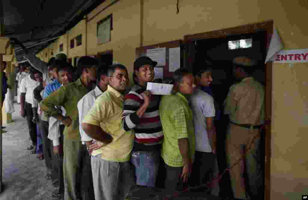 A first time voter displays his voting pass as he stands in a line to cast his vote during the first phase of elections in Dibrugarh, in the northeastern state of Assam, India, April 7, 2014. 