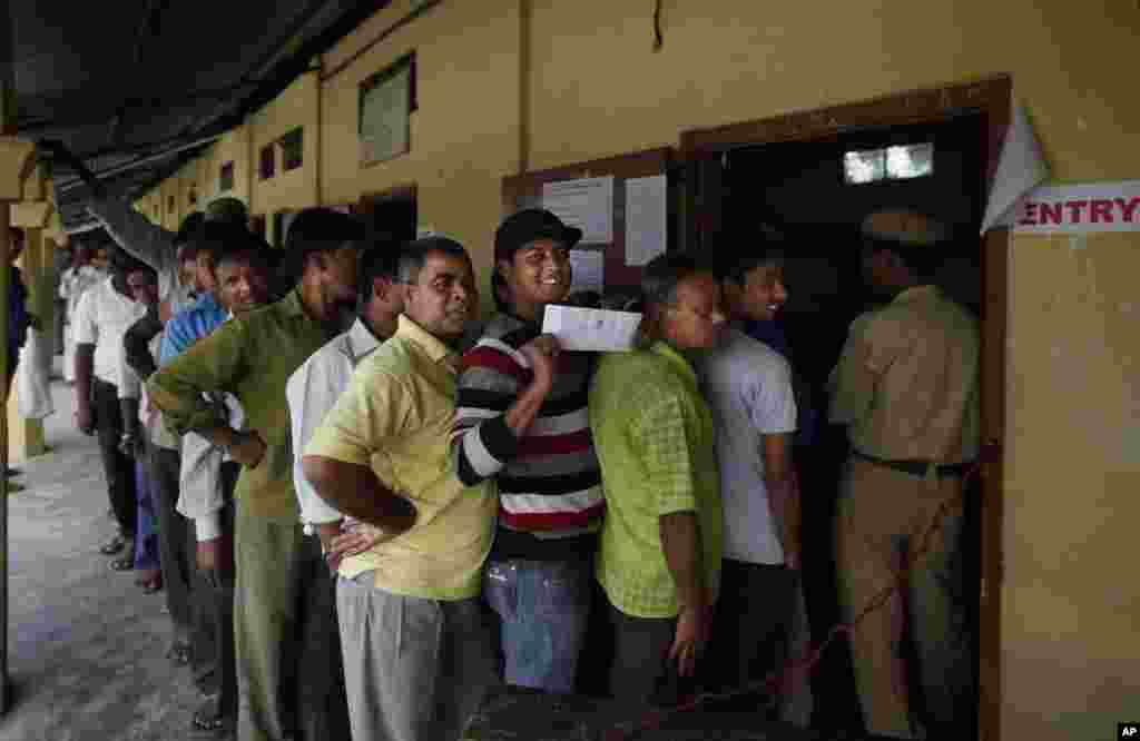 A first time voter displays his voting pass as he stands in a line to cast his vote during the first phase of elections in Dibrugarh, in the northeastern state of Assam, India, April 7, 2014.