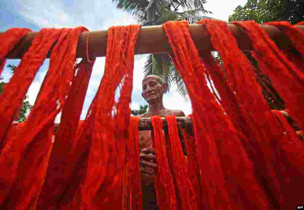 A worker hangs dyed yarns to dry at a textile mill on the outskirts of Agartala, India, on July 24, 2019.
