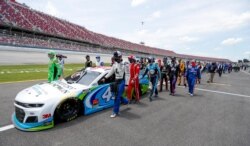 Nascar drivers Kyle Busch, left, and Corey LaJoie, right, join other drivers and crews as they push the car of Bubba Wallace to the front of the field prior to the start of the NASCAR Cup Series auto race at the Talladega Superspeedway, June 22, 2020