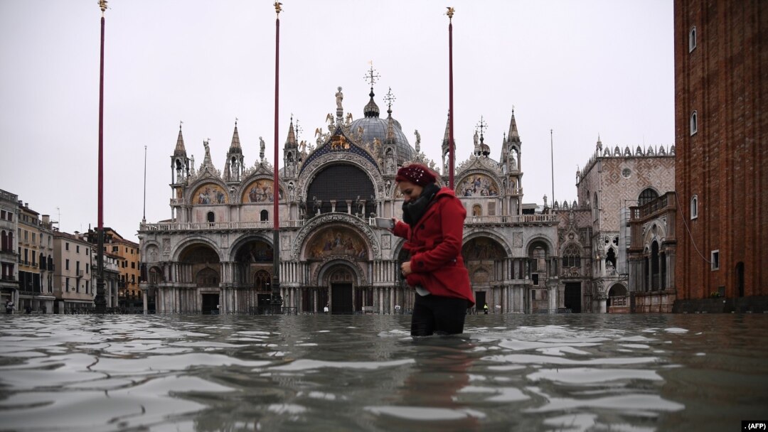 Seorang wanita melintasi alun-alun St. Mark yang dibanjiri oleh Basilika Santo Markus setelah ketinggian air pasang semalam "Alta Acqua", awal 13 November 2019 di Venesia. (Foto: AFP)