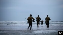 World War II reenactors walk on Omaha Beach in Saint-Laurent-sur-Mer, Normandy, France, Tuesday, June 6, 2023. Nearly 160,000 Allied troops landed on the shores of Normandy at dawn on June 6, 1944.