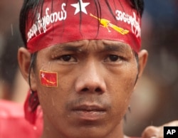 A supporter of of Myanmar's National League for Democracy party, waits in pouring rain outside the NLD headquarters in Yangon, Myanmar, Monday, Nov. 9, 2015.