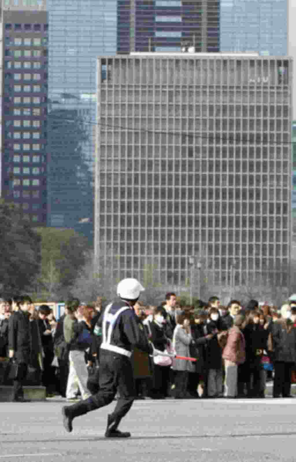 Un policía mantiene la calma de la gente durante la evacuación de los edificios en el distrito financiero de Tokyo.