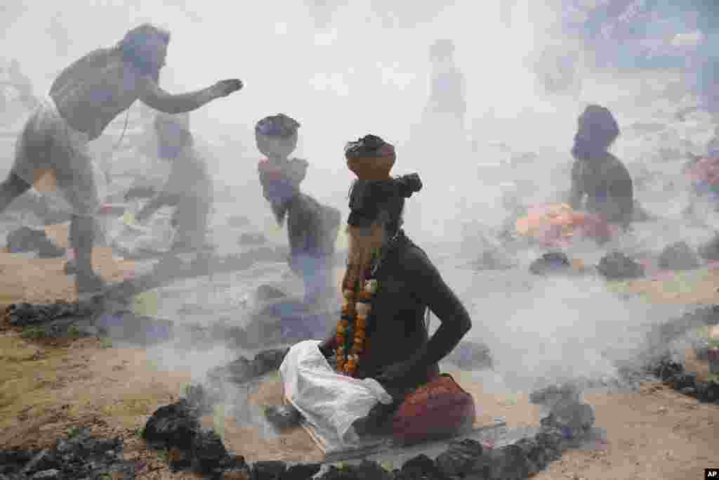 Sadhus, or Hindu holy men, perform a ritual by burning dried cow dung cakes in earthen pots at Sangam, confluence of rivers Ganges, Yamuna, and mythical Saraswati, at the annual traditional fair of Magh Mela in Allahabad, India.