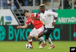 Pemain Prancis Paul Pogba (kanan), berebut bola dengan pemain Rusia Fyodor Smolov dalam pertandingan persahabatan internasional antara Rusia dan Prancis di stadion Saint Petersburg di St.Petersburg, Rusia, Selasa, 27 Maret 2018. (AP Photo/Dmitri Lovetsky)