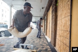 Perry Williams, 47, left, and Alaric Nixon, 28, place sandbags on the storefront of Diamond's International store, in preparation for the arrival of hurricane Joaquin in Nassau, Bahamas, Oct. 1, 2015.