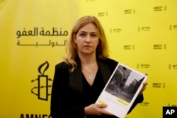 Anna Neistat, Amnesty International's senior director of global research, poses for photographers as she shows a magazine cover during a press conference in Beirut, Lebanon, Oct. 12, 2018.