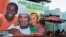 Women sell food in front of a poster for presidential candidate Ibrahim Boubacar Keita in Bamako, July 16, 2013. The poster reads, "For the happiness of Mali." 