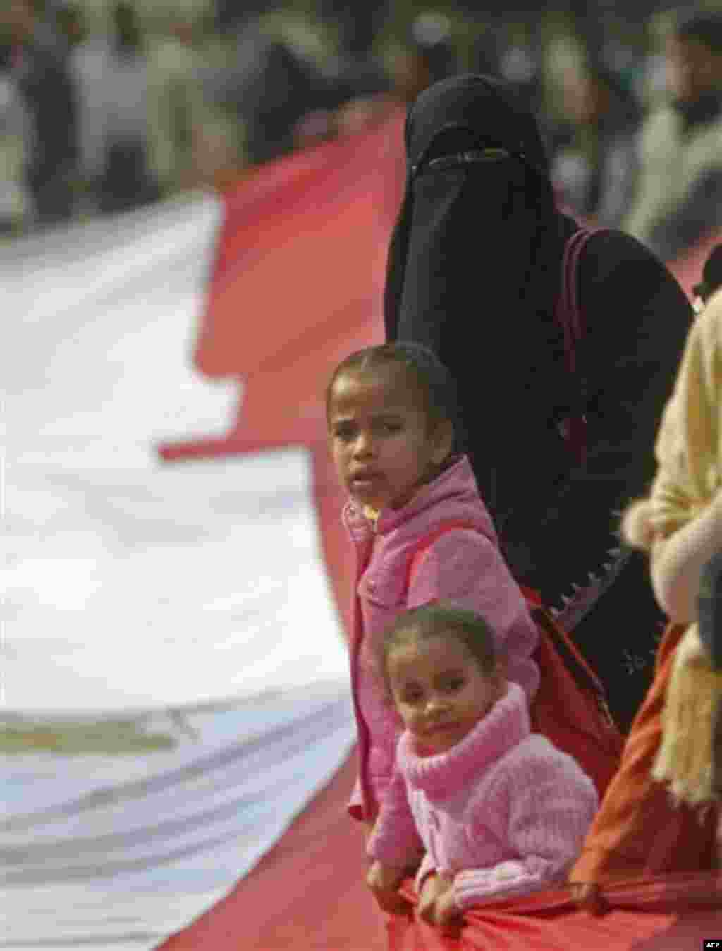 An Egyptian protester and her childern wave a giant Egyptian flag in front of the Egyptian Parliament in Cairo, Egypt, Wednesday, Feb. 9, 2011. Around 2,000 protesters waved huge flags outside the parliament, located several blocks from Tahrir Square, whe