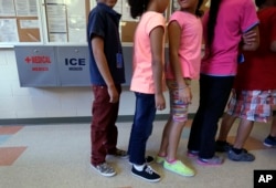 FILE - In this Sept. 10, 2014 file photo, detained immigrant children line up in the cafeteria at the Karnes County Residential Center, a temporary home for immigrant women and children detained at the border, in Karnes City, Texas.