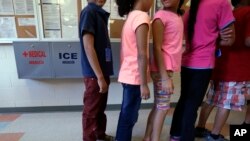 FILE - In this Sept. 10, 2014 file photo, detained immigrant children line up in the cafeteria at the Karnes County Residential Center, a temporary home for immigrant women and children detained at the border, in Karnes City, Texas.