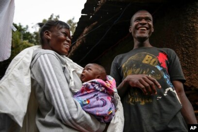 Veronica Atieno, kiri, menggendong putrinya Shaniz Joy Juma, tengah, yang dilahirkan sebulan sebelumnya oleh dukun bayi tradisional selama jam malam menjelang senja, ditemani suaminya Gabriel Owour Juma, kanan, di daerah kumuh Kibera di Nairobi. (Foto: AP)