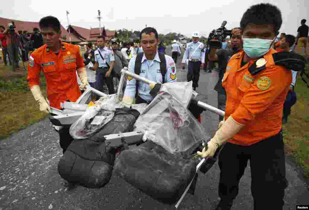 Bagian dari pesawat AirAsia bernomor penerbangan 8501, yang diambil dari Laut Jawa, diangkut dari helikopter Angkatan Laut AS di bandar udara di Pangkalan Bun, Kalimantan Tengah (5/1).​(Reuters/Darren Whiteside)