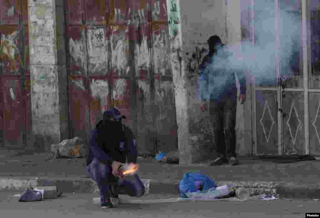 A protester lights fire crackers during clashes with Israeli troops following an anti-Israel demonstration in the West Bank city of Hebron, Nov. 14, 2014.