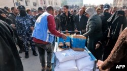 FILE - Workers of the United Nations Relief and Works Agency for Palestine Refugees hand out flour rations and other supplies to people at an UNRWA warehouse in Rafah in the southern Gaza Strip on December 12, 2023.