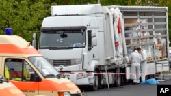 Policemen investigate a truck near a police station in Frankfurt, Germany, Sept. 16, 2017. Germany’s federal police say they stopped the truck near the German-Polish border with 51 people inside, among them 17 children. 