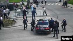 Сотрудники службы безопасности сажают раненого Роберта Фицо в автомобиль. Хандлова, Словакия. 15 мая 2024 г. 