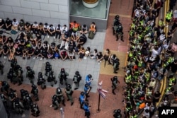 Riot police detain a group of people (top L) as the media (R) looks on during a protest in the Causeway Bay district of Hong Kong on May 27, 2020, as the city's legislature debates over a law that bans insulting China's national anthem.