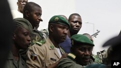 Lieutenant Amadou Konare, centre, spokesman for coup leader Amadou Haya Sanogo, unseen, is surrounded by security as he arrives to address supporters, as thousands rallied in a show of support for the recent military coup, in Bamako, Mali, March 28, 2012.