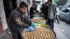 Seorang penjual sedang memilah-milah kue kering di nampan di luar toko roti di Deir el-Balah di Jalur Gaza sementara orang-orang bersiap untuk merayakan hari raya Idul Fitri, di tengah konflik Israel-Hamas. 