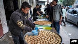 Seorang penjual sedang memilah-milah kue kering di nampan di luar toko roti di Deir el-Balah di Jalur Gaza sementara orang-orang bersiap untuk merayakan hari raya Idul Fitri, di tengah konflik Israel-Hamas. 