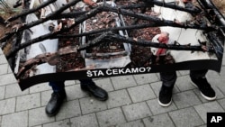 Members of the Independent Journalists' Association hold a poster shows a journalist Milan Jovanovic in his burned house that reads: "What are we waiting for?" during a protest in Belgrade, Serbia, Dec. 12, 2019.