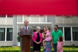 FILE - In this June 28, 2017, file photo, U.S. Ambassador to China Terry Branstad, left, speaks during a briefing to journalists near his family at the Ambassador's residence in Beijing.