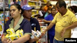 People hold their groceries as they line up to pay the cashier at a supermarket in Caracas, Veneuela, Aug. 21, 2014.