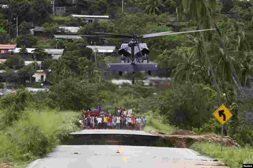 Warga yang terjebak menunggu sementara helikopter mendarat di dekat di jalan yang ambruk di Coyuca de Benitez, sekitar 35 km dari Acapulco, Meksiko. Wilayah Acapulco tengah dilanda bencana banjir akibat badai tropis Manuel.