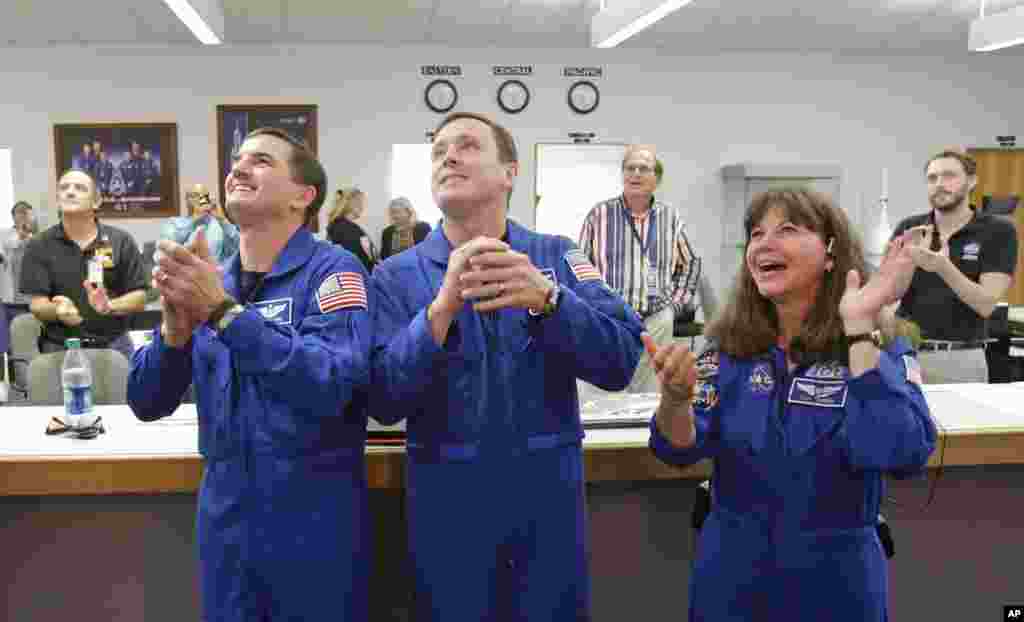 NASA astronauts, from left, Rex Walheim, Jack Fischer and Cady Coleman, cheer as they watch the landing of the Orion test flight on a television at the Press Site at the Kennedy Space Center, Friday, Dec. 5, 2014.