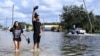 FILE - Neryliz Rivera, left, and Luis Arroyo walk through a flooded city street in the aftermath of Hurricane Helene, Sept. 27, 2024, in Crystal River, Fla. 