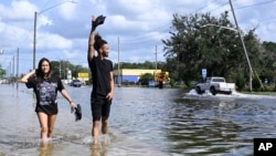 FILE - Neryliz Rivera, left, and Luis Arroyo walk through a flooded city street in the aftermath of Hurricane Helene, Sept. 27, 2024, in Crystal River, Fla. 