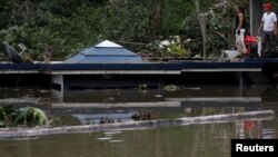 Men stand at the roof of a house submerged by floodwaters close to the Guajataca Dam after the area was hit by Hurricane Maria in Guajataca, Puerto Rico, Sept. 23, 2017. 