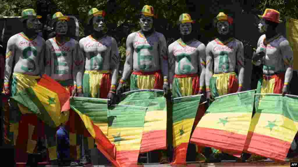 Des artistes sénégalais posent avec le drapeau du Sénégal devant les portes du Palais présidentiel à Dakar, le 11 mars 2018.