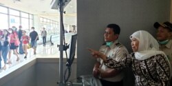 Gubernur Jawa Timur Khofifah Indar Parawansa mengamati monitor pemantau suhu tubuh penumpang pesawat yang baru tiba di Bandara Juanda (foto Petrus Riski/VOA)