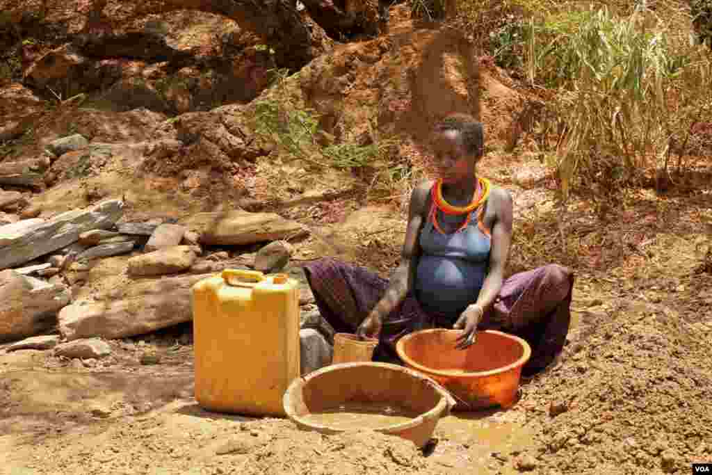 A Karimojong woman pans for gold using two plastic basins, March 2, 2014. Hilary Heuler / VOA News
