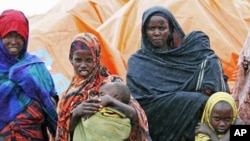 An internally displaced Somali family stand in the rain outside their makeshift shelter in the south of Mogadishu's Hodan district, August 2, 2011