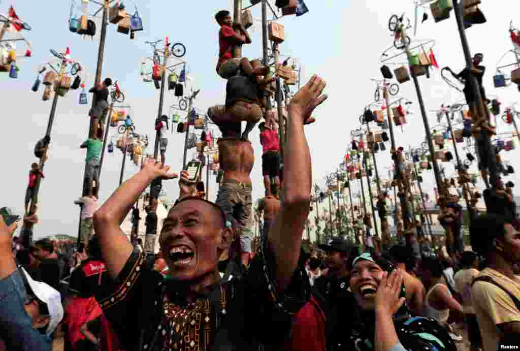 A couple reacts as their colleague wins a bicycle during greased pole competition during the celebration of Independence Day at Ancol Dreamland Park in Jakarta, Indonesia.